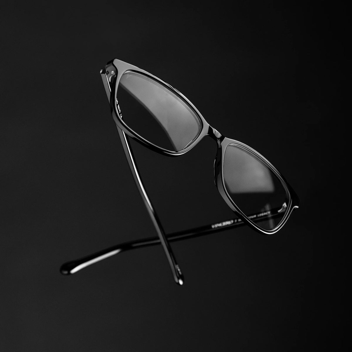 Black sunglasses on a black stand against a black background