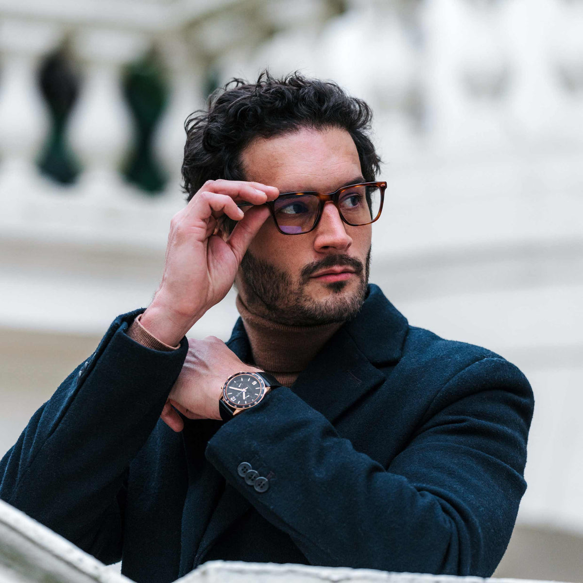 Man adjusting glasses with a blurred background