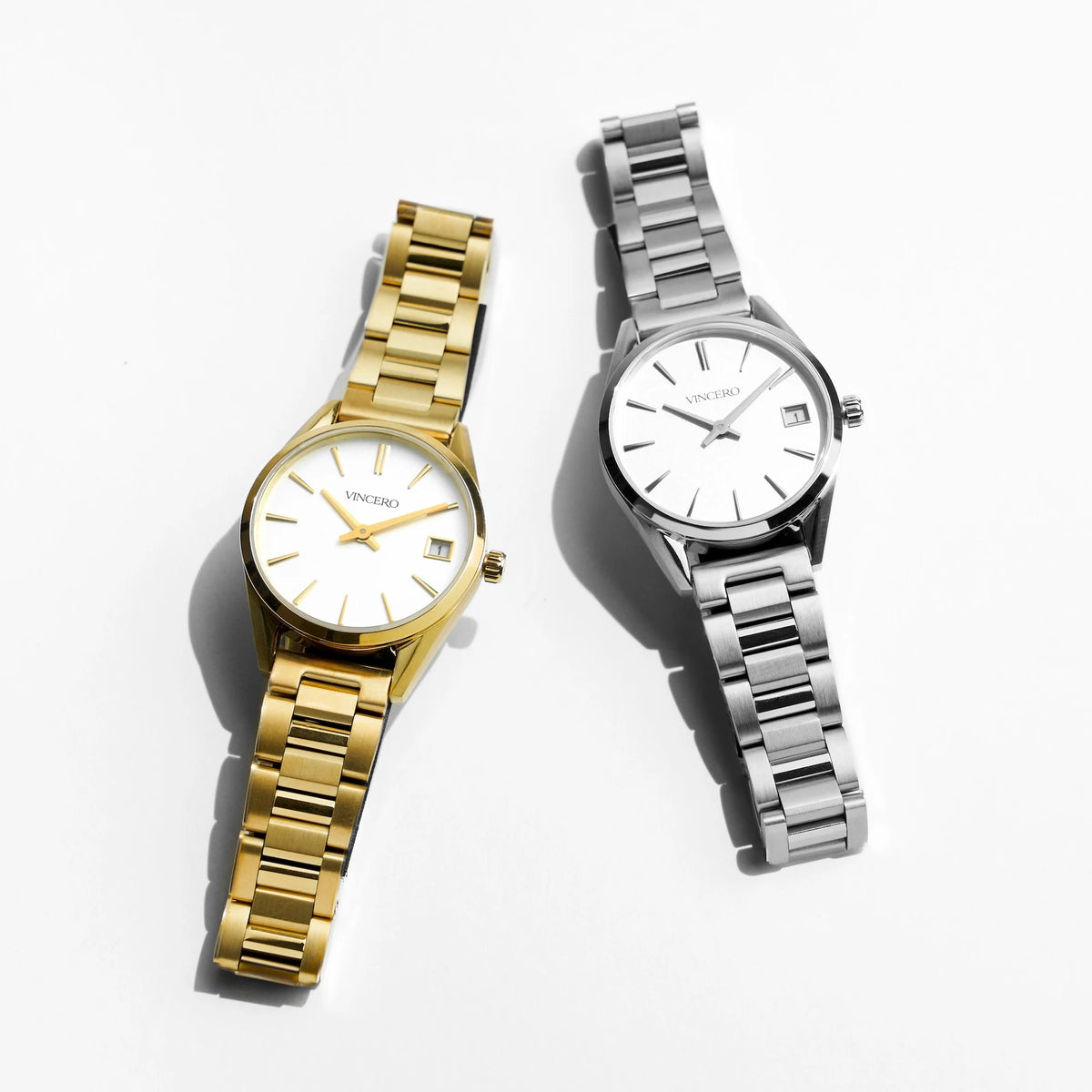 Two watches, one gold and one silver, on a white background