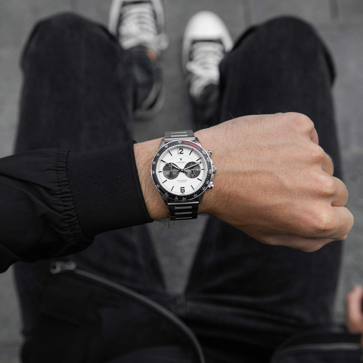 Person wearing a black wristwatch with a white face on a blurred background