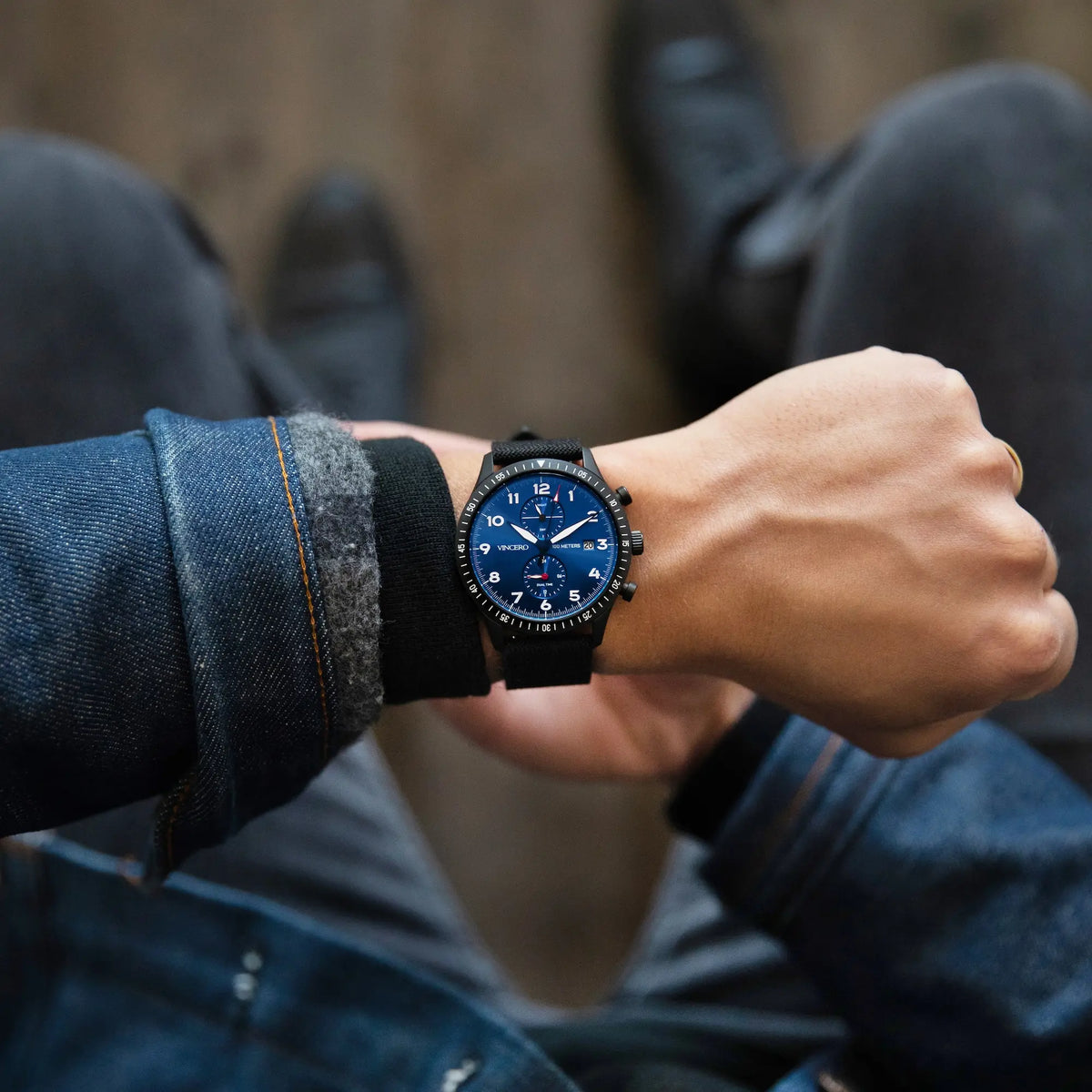 Person wearing a blue wristwatch with a blurred background