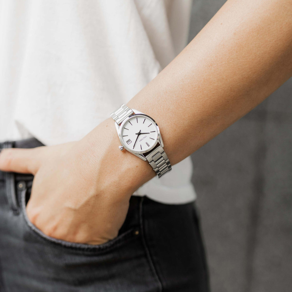 Person wearing a silver watch on a blurred background