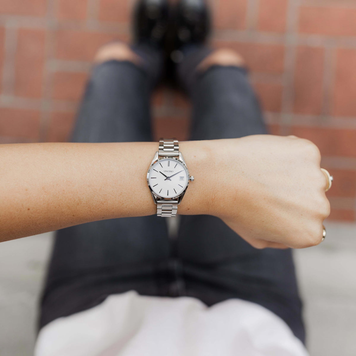 Person wearing a silver watch on a blurred background