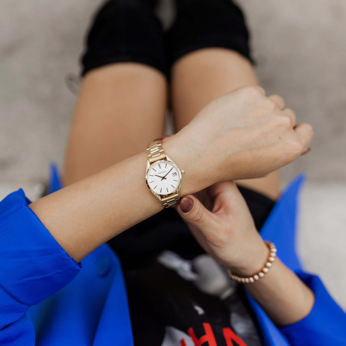 Person wearing a gold watch on a blurred background