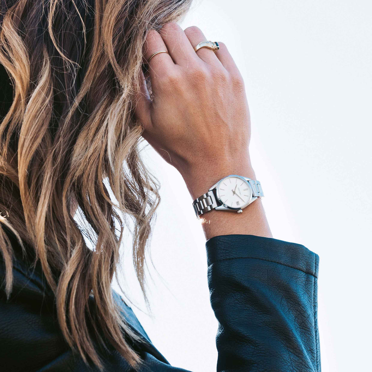 Close-up of a person wearing a silver watch on a blurred background