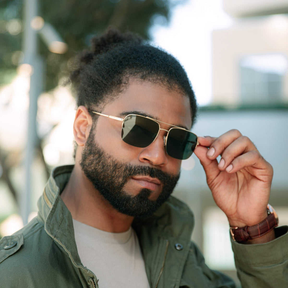Man wearing sunglasses and a green jacket with a blurred background