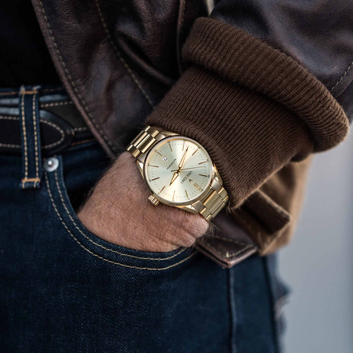 Gold wristwatch on a person's wrist with a blurred background