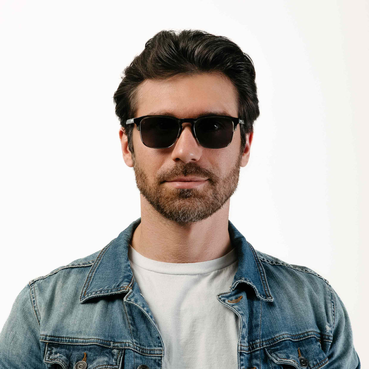 Man wearing sunglasses and a denim jacket on a white background