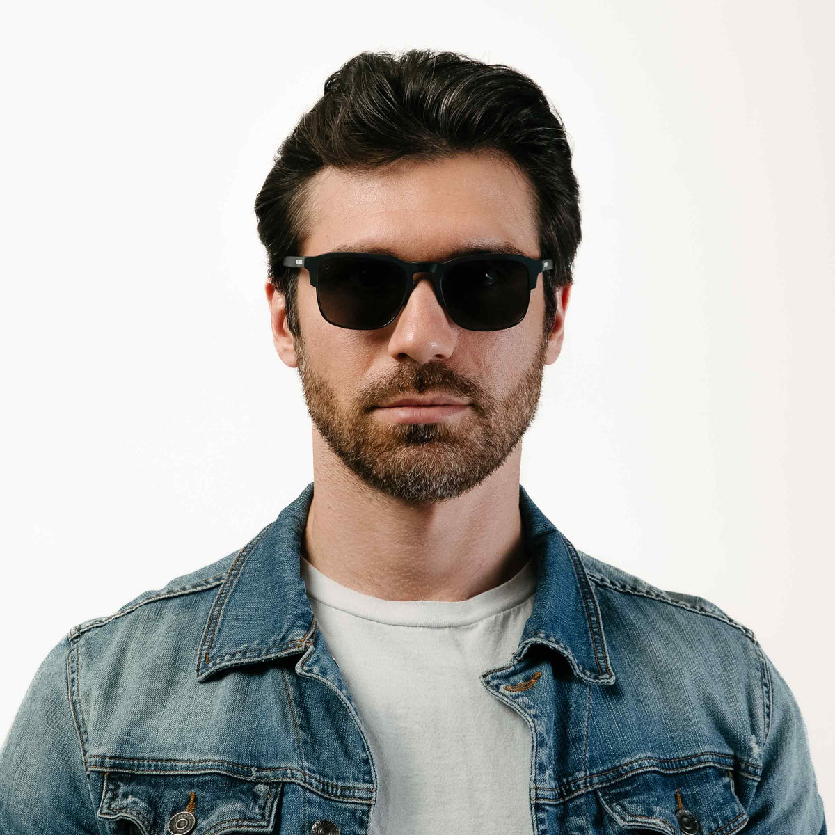 Man wearing sunglasses and a denim jacket on a white background