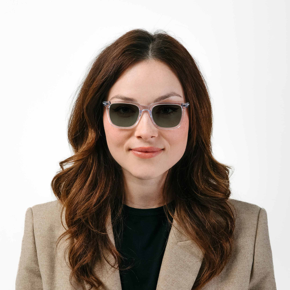 Woman wearing sunglasses and a beige blazer on a white background
