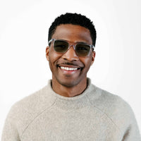 Man wearing sunglasses and a light gray sweater on a white background