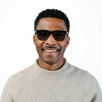 Man wearing sunglasses and a light gray sweater on a white background