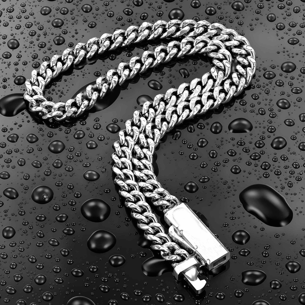 A silver-toned Cuban link chain necklace with a rectangular clasp, arranged on a glossy black surface covered in water droplets.
