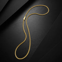 A gold curb chain necklace with a small rectangular clasp, arranged in a curved loop on a dark textured background.