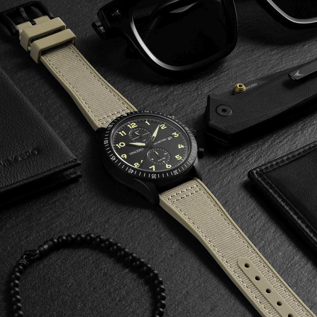 Watch with beige strap on a dark surface with wallet and knife