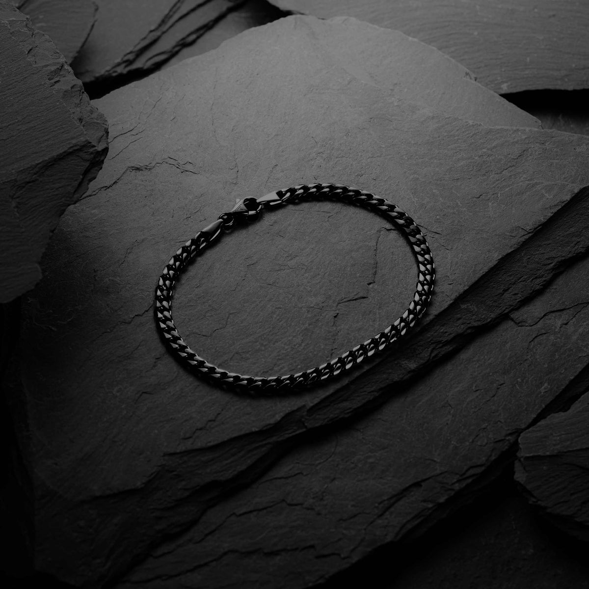 Silver chain bracelet on a dark stone surface