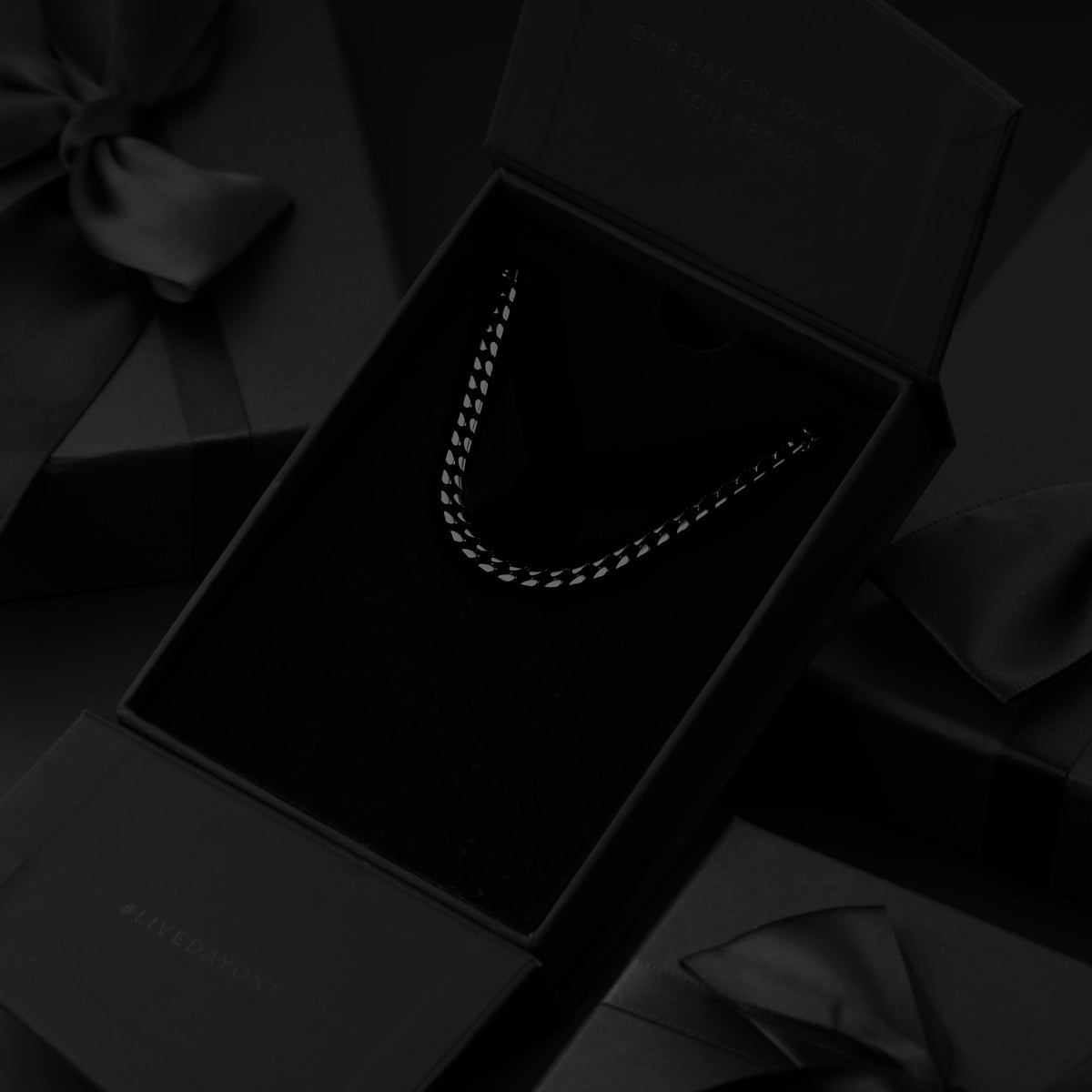 Black box with a necklace inside, on a black fabric background