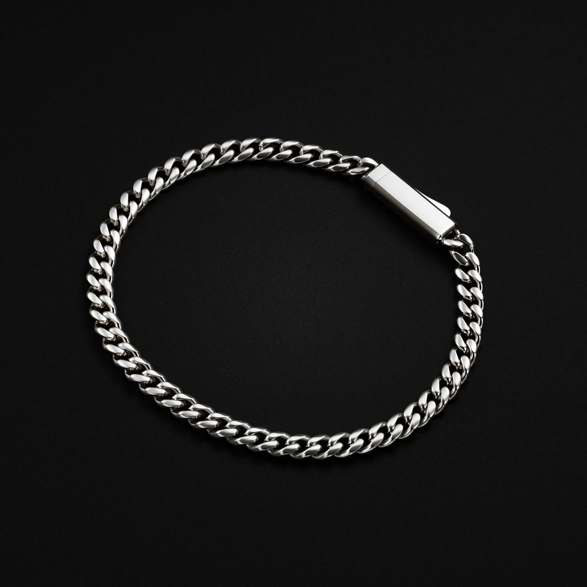 A silver-toned Cuban link chain bracelet with a polished rectangular clasp, displayed on a solid black background.