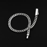A silver-toned Cuban link chain accessory with a rectangular clip on one end and a small key-shaped tag on the other, displayed on a solid black background.