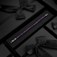 Purple beaded bracelet on a black surface with decorative bows