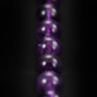 Close-up of a string of purple beads on a black background
