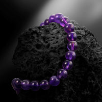 Purple beaded bracelet on a dark textured surface