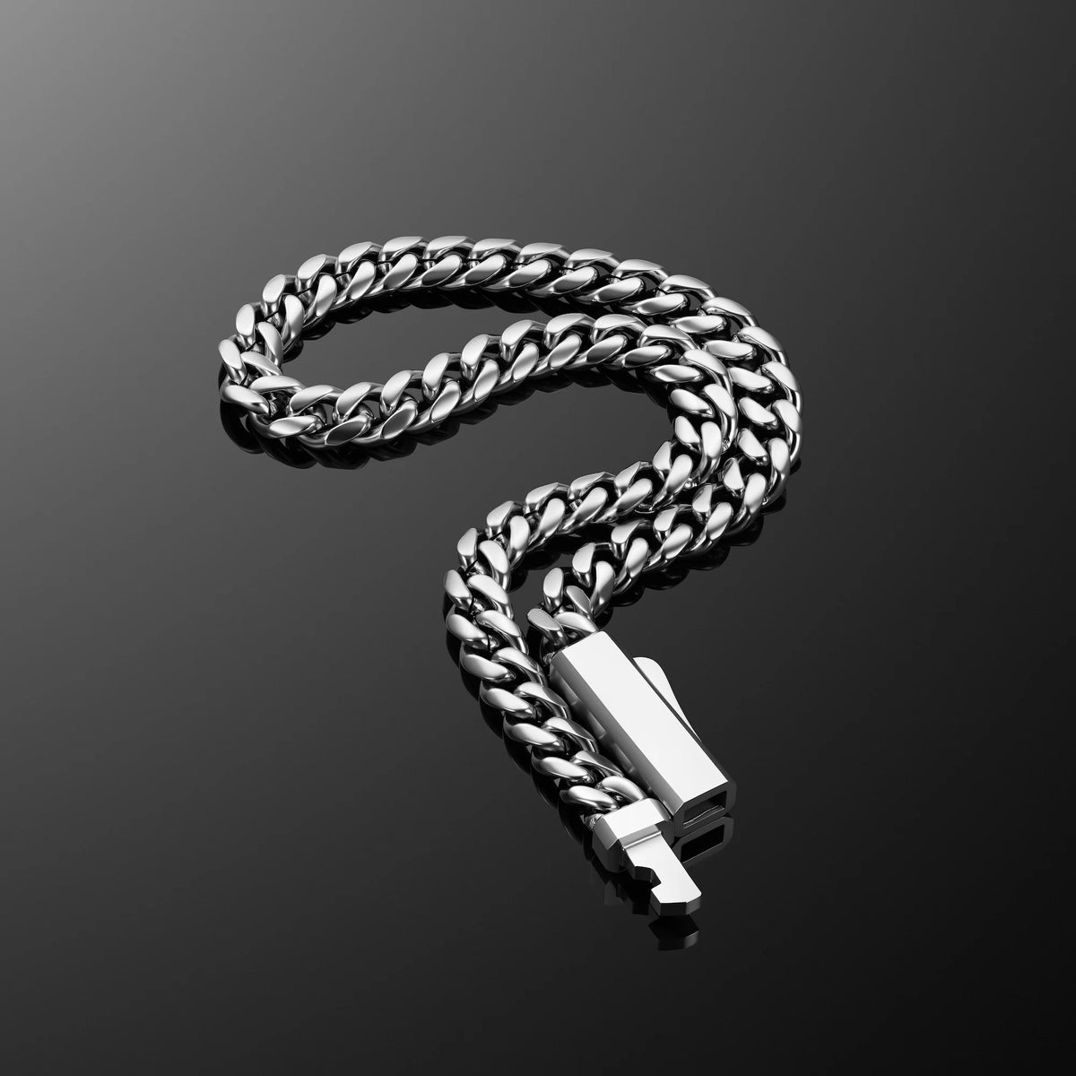 A silver-toned Cuban link chain necklace with a rectangular polished clasp, arranged in a curved loop on a dark reflective surface.