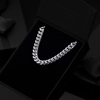 A silver-toned Cuban link chain necklace displayed inside an open black presentation box on a black velvet insert.