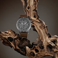 Watch with brown leather strap on a textured wooden surface