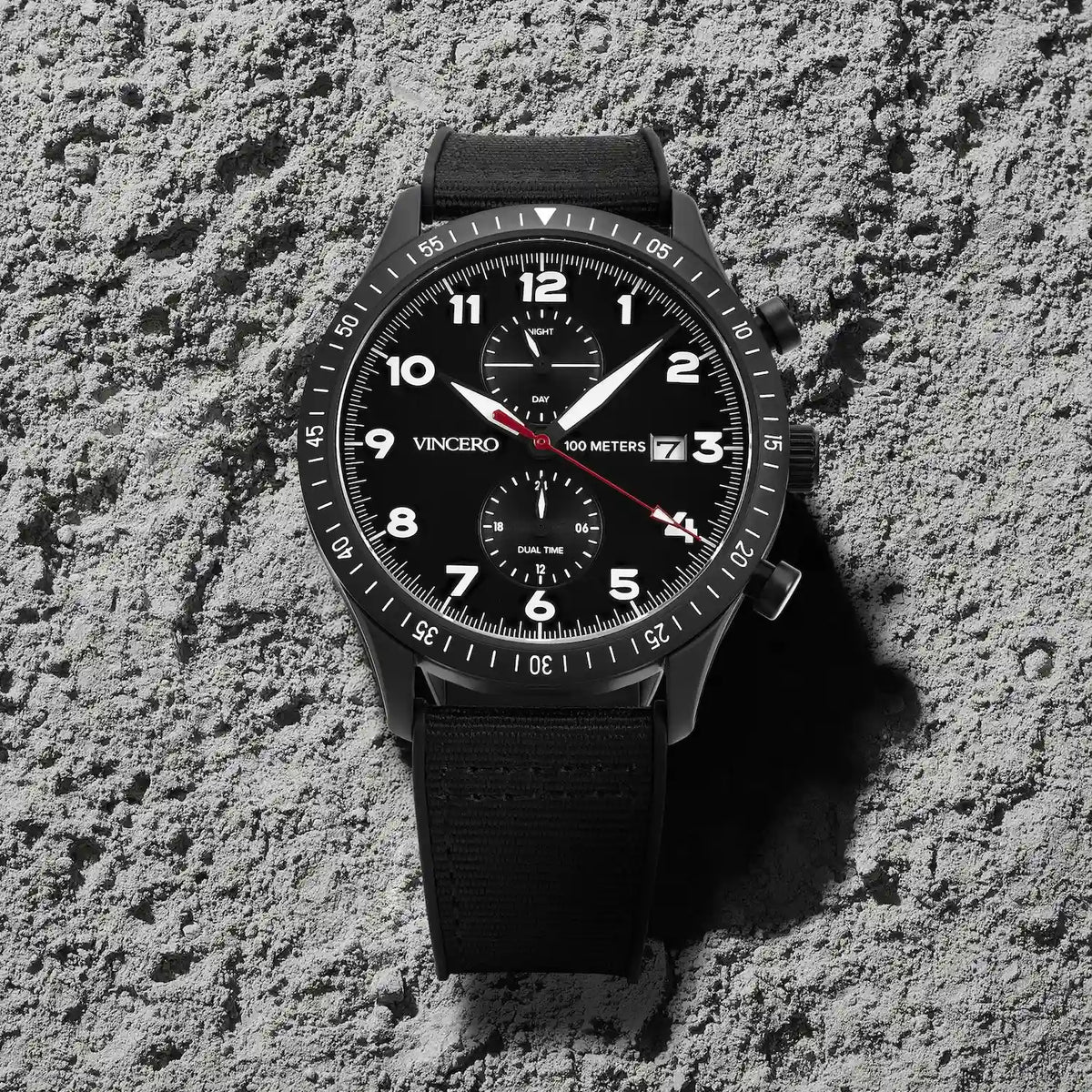 Black wristwatch with a detailed face on a textured gray surface