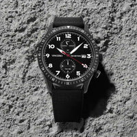 Black wristwatch with a detailed face on a textured gray surface