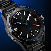A close-up of a VINCERO A-250 analog watch with a black metal case and link bracelet, featuring a black dial with white Arabic numerals, blue bezel markings, and a red second hand, set against a dark blue gradient background.