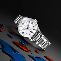 A stainless steel wristwatch with a white dial, featuring red and blue accents on the bezel and white dial, displayed diagonally on a dark gray background with red and blue liquid splash props.