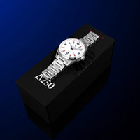 A silver stainless steel wristwatch with a white dial and date window, resting diagonally on a black branded box against a dark blue gradient background.