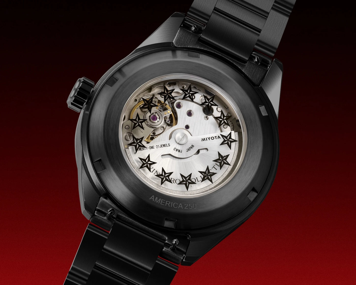 Close-up of a black ceramic watch with a transparent back, showing the white mechanical movement and star-shaped hands, on a red gradient background.