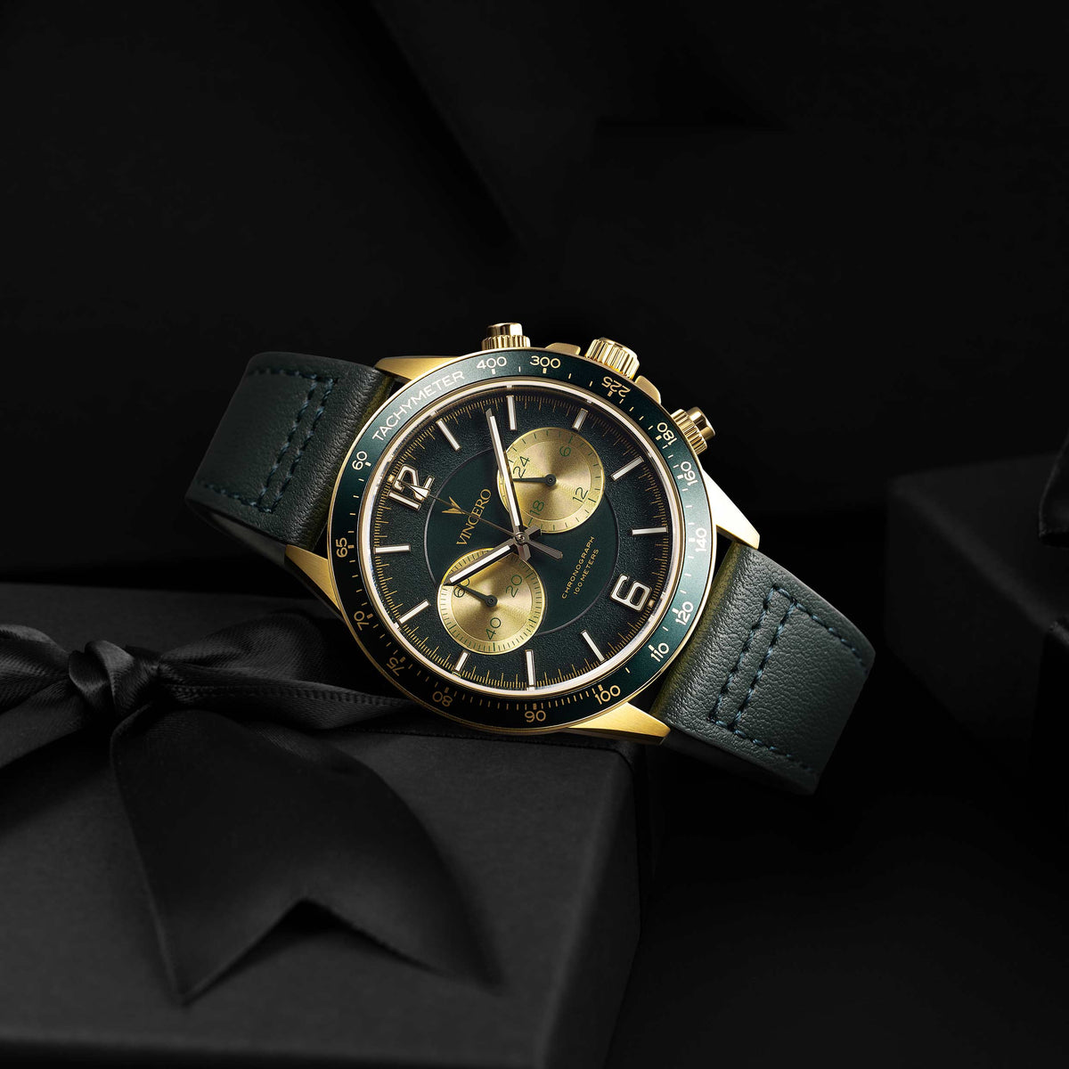Luxury watch with green and gold face on a black background