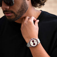 Man wearing a watch with a black shirt and sunglasses, close-up of wrist and face.