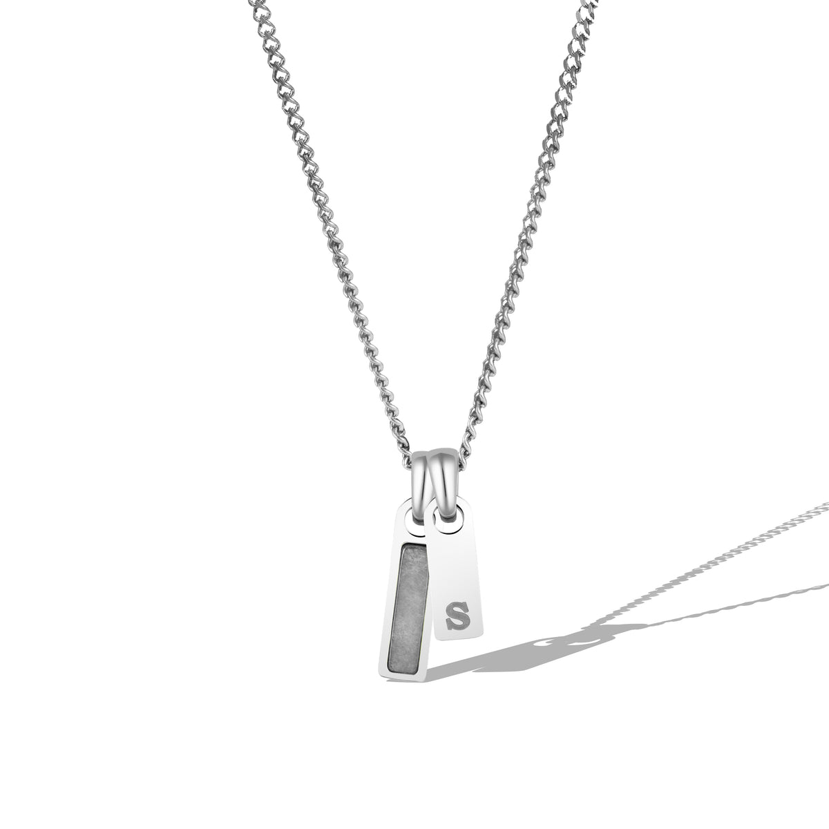 A silver necklace with a rectangular tag pendant featuring a birthstone and a chain link.