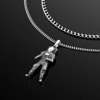 Silver astronaut pendant on a chain against a black background
