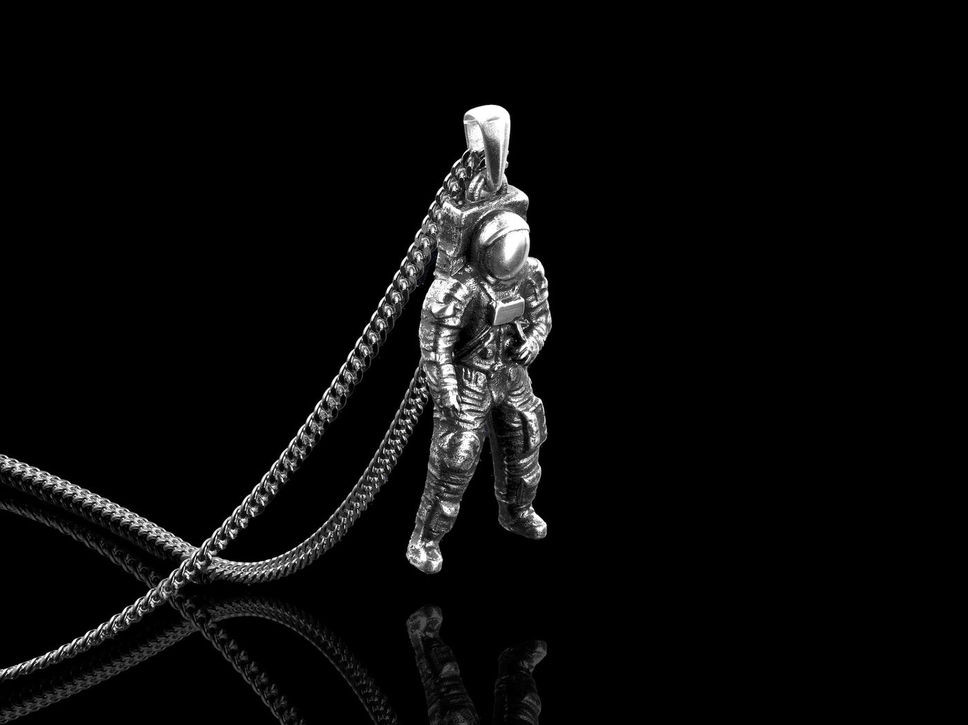Silver astronaut pendant on a black background