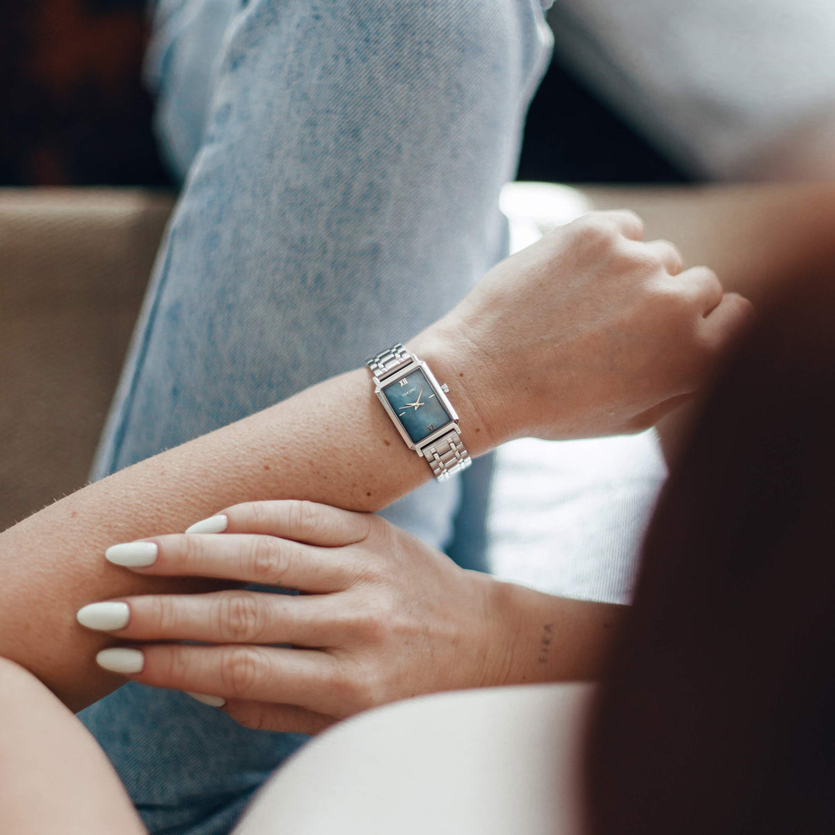 Close-up of a person's wrist wearing a watch with a blurred background