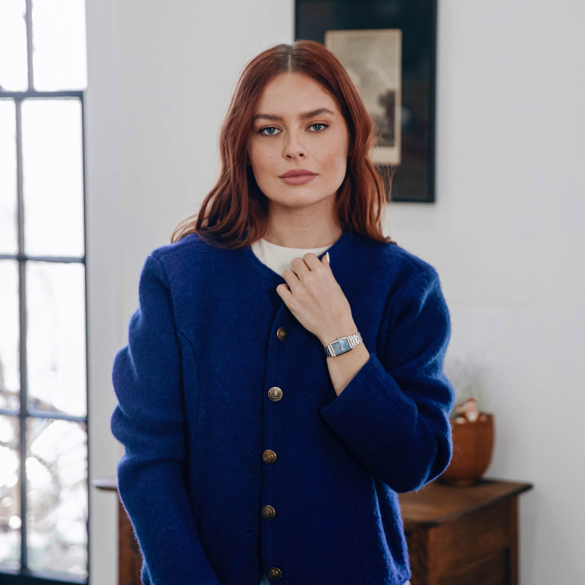 Woman wearing a blue coat indoors with a neutral background