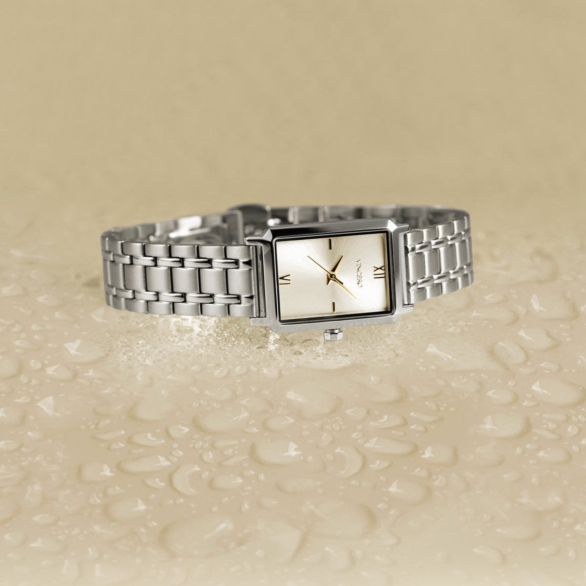 Silver watch with a rectangular face on a beige textured surface