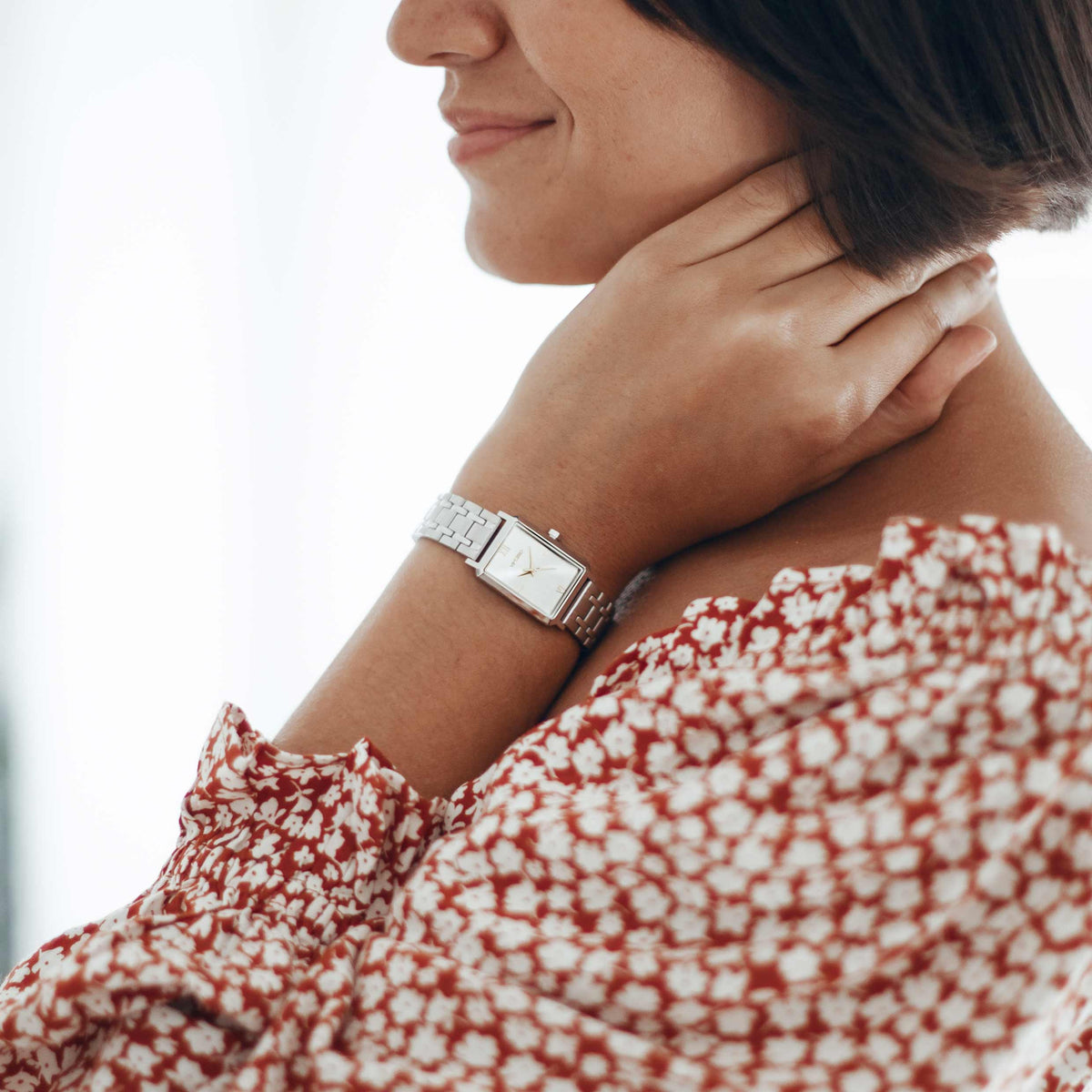 Woman wearing a silver watch with a blurred background