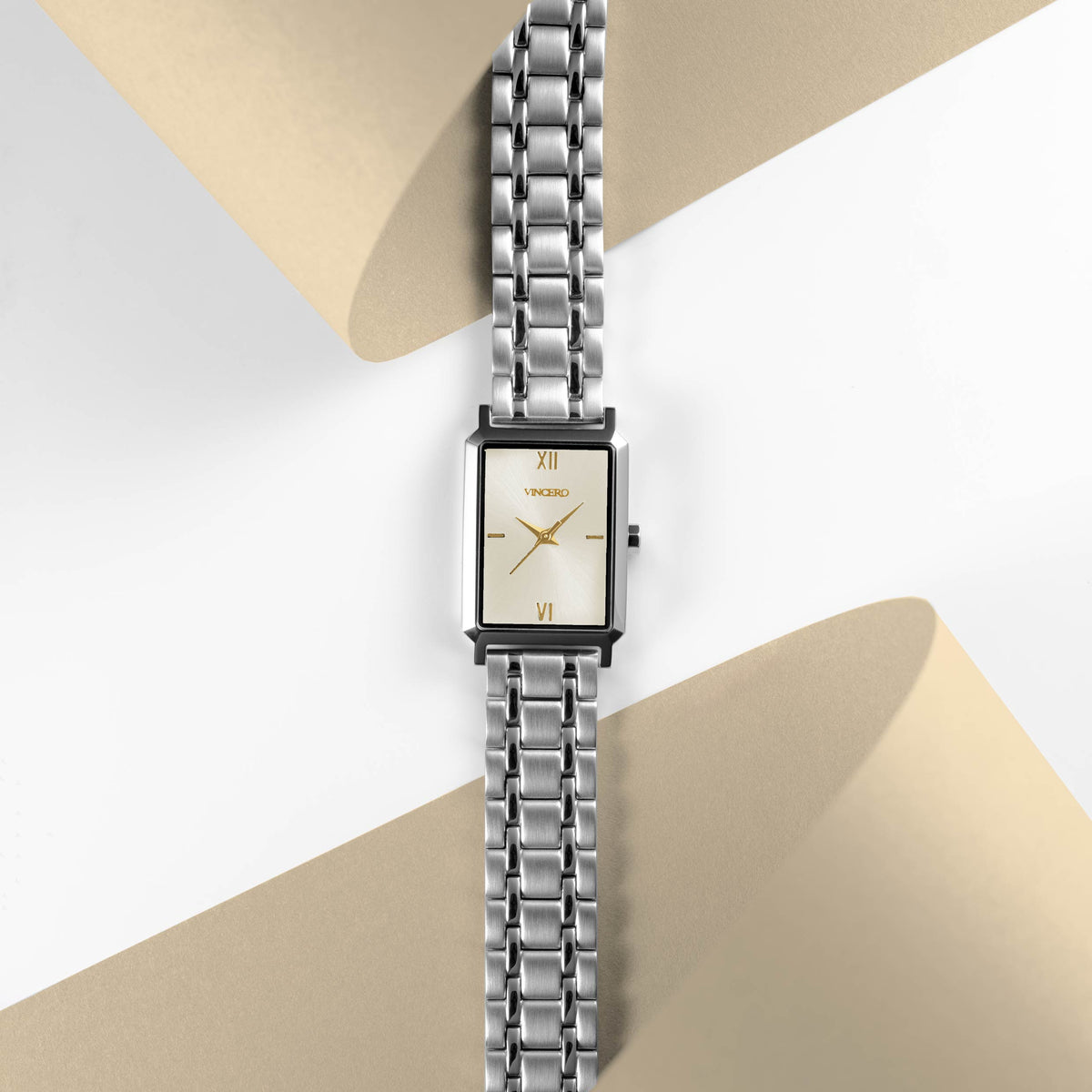 Silver watch with a beige face on a beige and white background