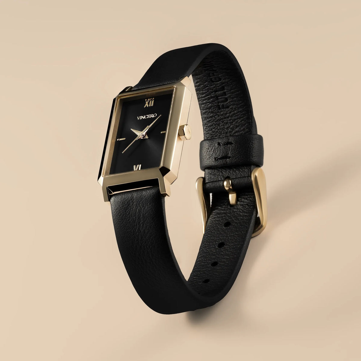 Black wristwatch with gold accents on a beige background