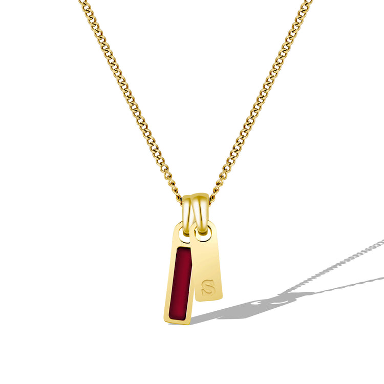 Gold necklace with a red pendant on a white background