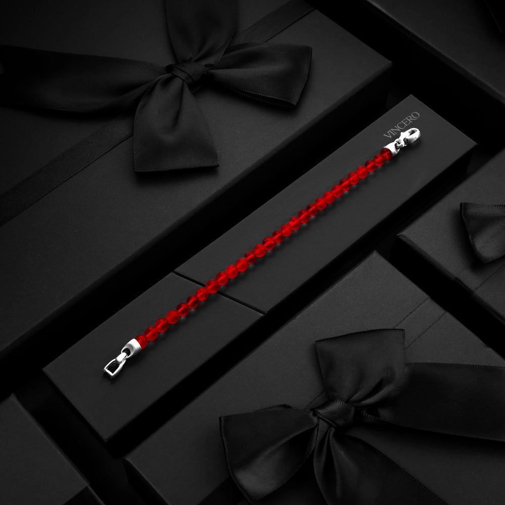 Red bracelet with silver clasp on a black box with black ribbons