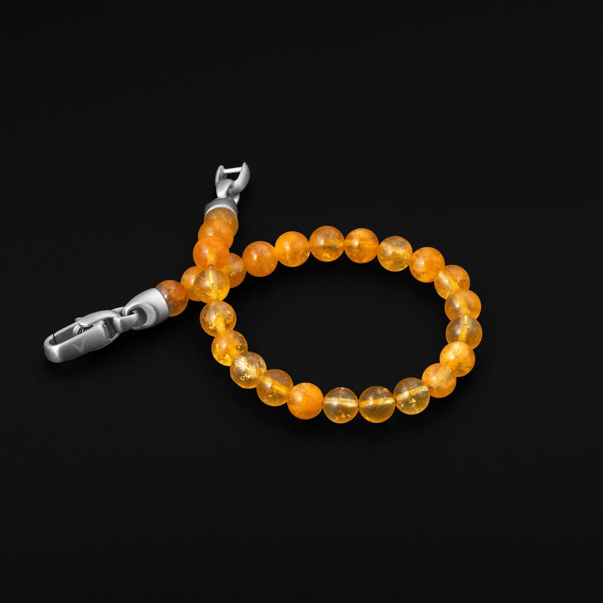 Orange beaded bracelet with silver clasp on a black background