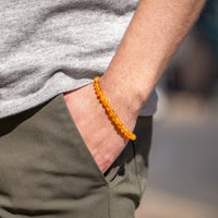 Person wearing a yellow beaded bracelet on a blurred background